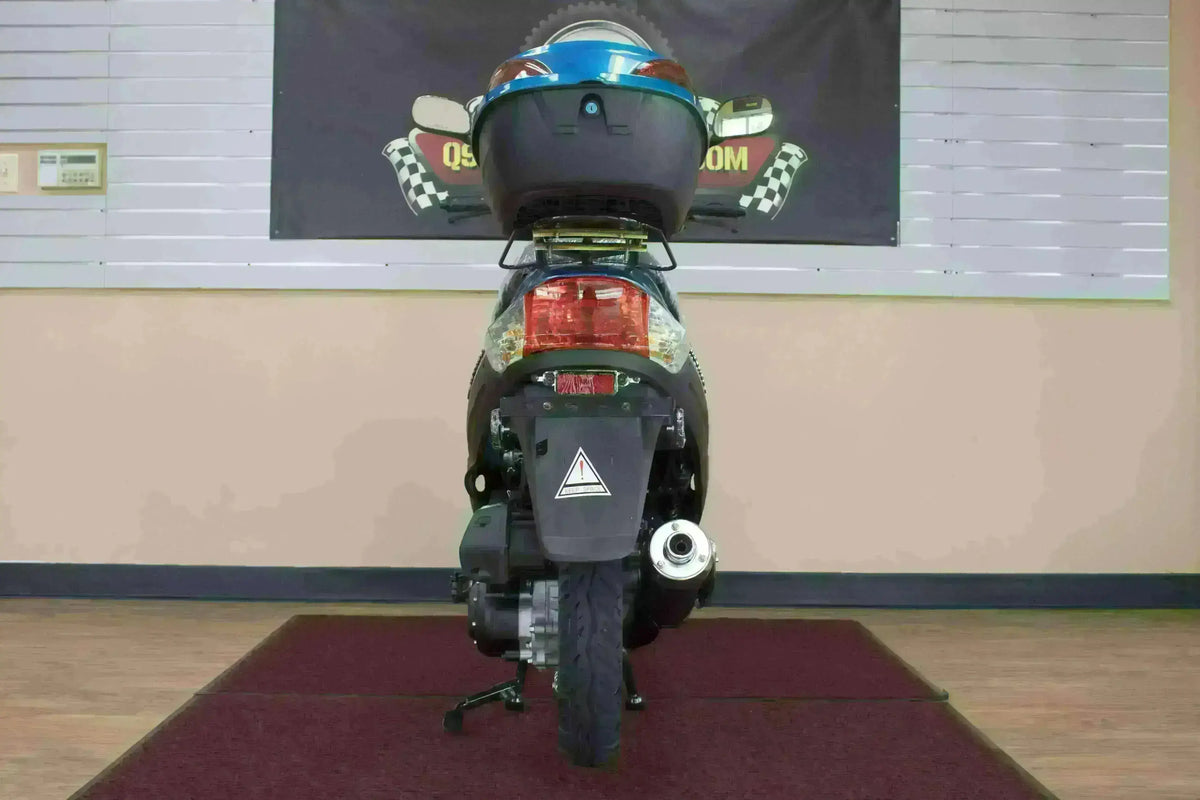 Rear view of 50cc campus cruiser scooter with top case, tail light, and exhaust visible indoors.