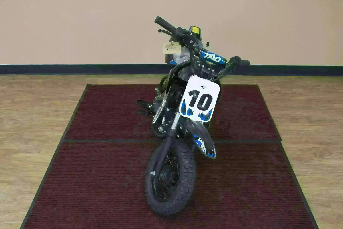 Blue and black 110cc kids dirt bike with number 10 plate on display indoors