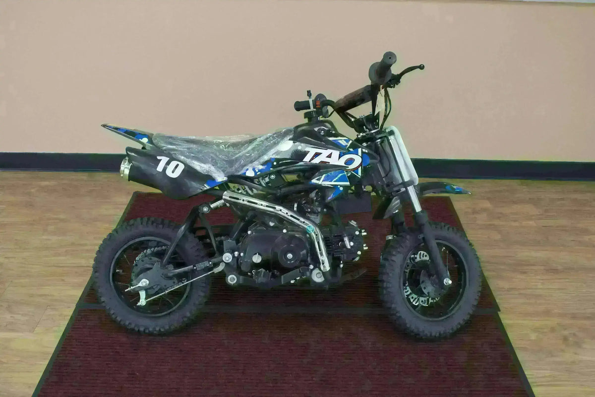 Blue and black 110cc kids dirt bike with knobby tires on indoor mat