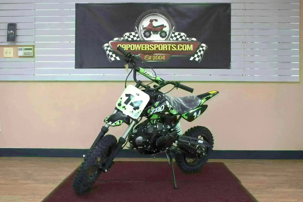 Green and black youth dirt bike with number 14, indoors on display with off-road tires