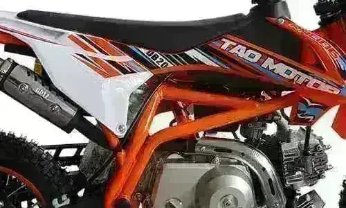 Close-up of orange Tao Motor DB20 kids dirt bike with detailed engine and graphics.