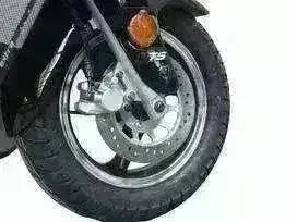 Close-up of a 50cc scooter front wheel with disc brake and black tire