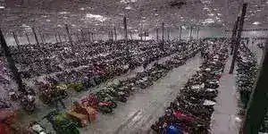 Warehouse interior with rows of ATVs, dirt bikes, go-karts, and scooters lined up.