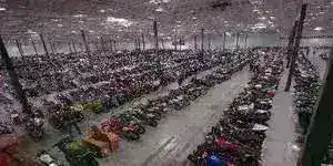 Warehouse interior with rows of ATVs, dirt bikes, go-karts, and scooters lined up.