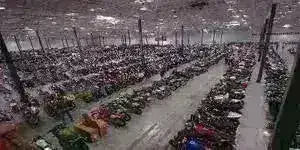 Warehouse interior with rows of ATVs, dirt bikes, go-karts, and scooters lined up.