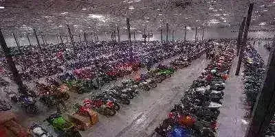 Large indoor warehouse filled with rows of motorcycles, scooters, and ATVs.
