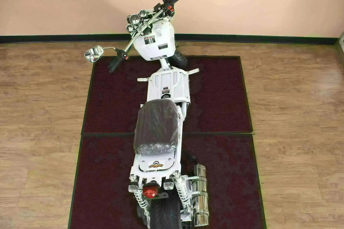 Top view of a white 50cc gas scooter with dual rear shocks and chrome exhaust indoors