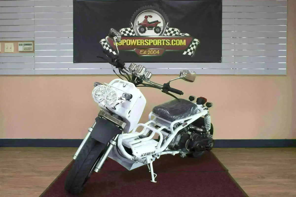 White 50cc scooter with dual headlights on showroom floor, exposed frame style, mirrors visible