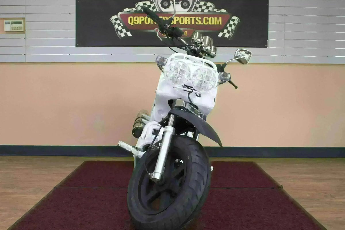 Front view of a white Maddog 50cc scooter with dual headlights indoors