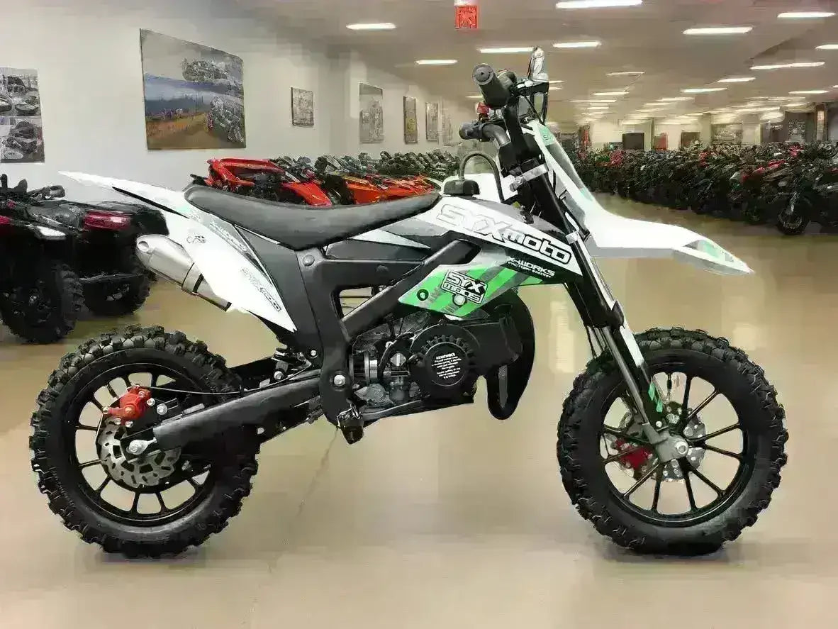 Youth dirt bike with knobby tires and SX Moto graphics on showroom floor