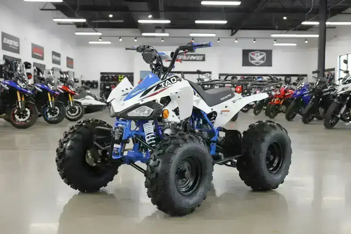 White and blue 125cc youth off-road ATV with knobby tires in a showroom