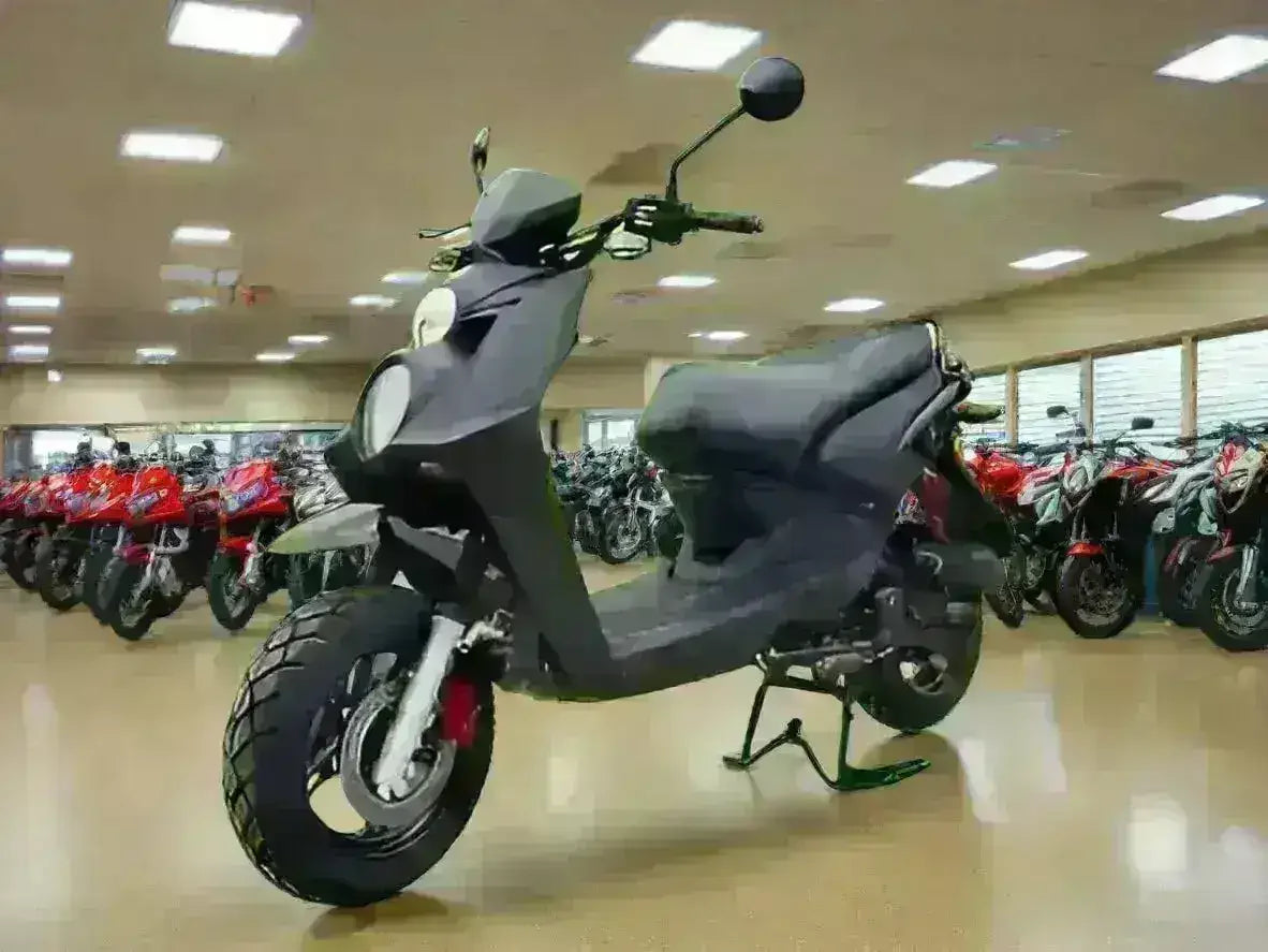 Black road-legal scooter parked indoors among motorcycles, modern showroom setting
