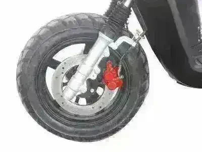 Close-up of scooter front wheel with disc brake and red caliper