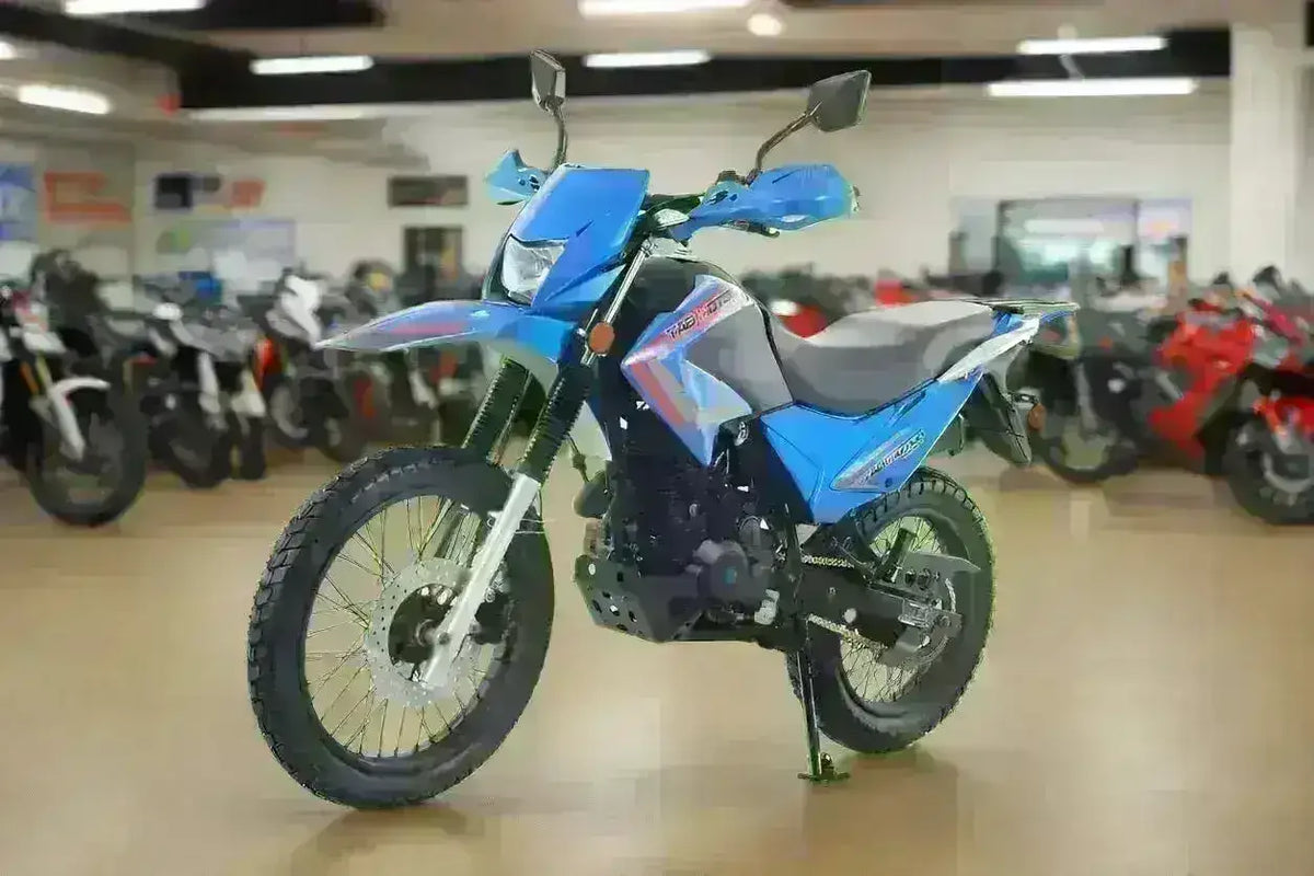 Blue 250cc dual sport motorcycle on display indoors with off-road tires and mirrors