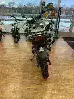 Rear view of a road-legal 250cc motorcycle with knobby tires displayed indoors