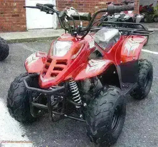 Red 110cc kids 4-wheeler ATV parked outdoors with rugged tires and front suspension.
