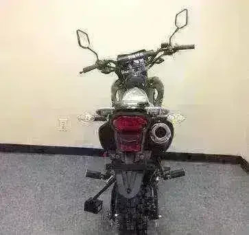 Rear view of a black 250cc dirt bike with knobby tires and dual mirrors in an indoor setting