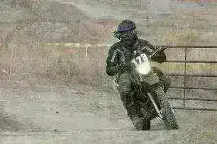 Rider wearing gear on a black 250cc dirt bike, off-road on a dusty trail