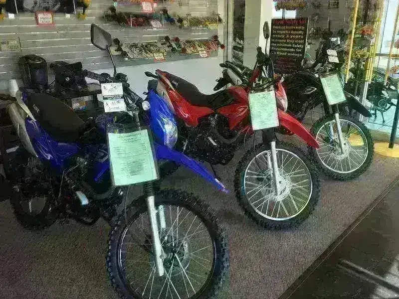 250cc dirt bikes with knobby tires on showroom floor, available in blue, red, and black.