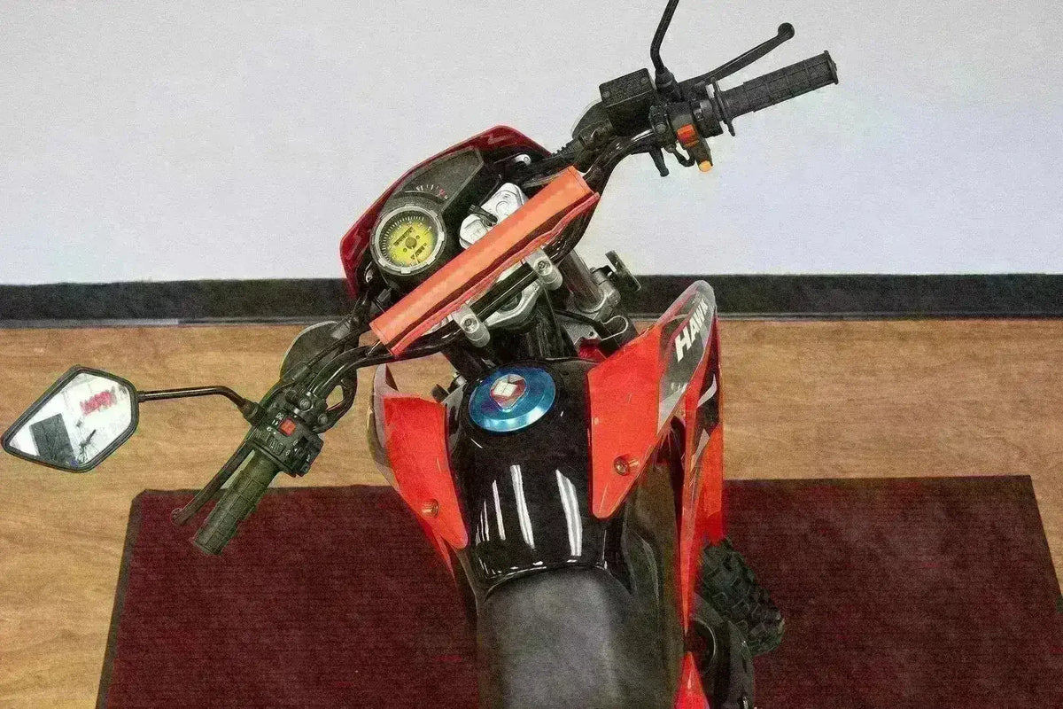 Red 250cc dirt bike handlebars and dashboard, enduro style, indoor showroom setting