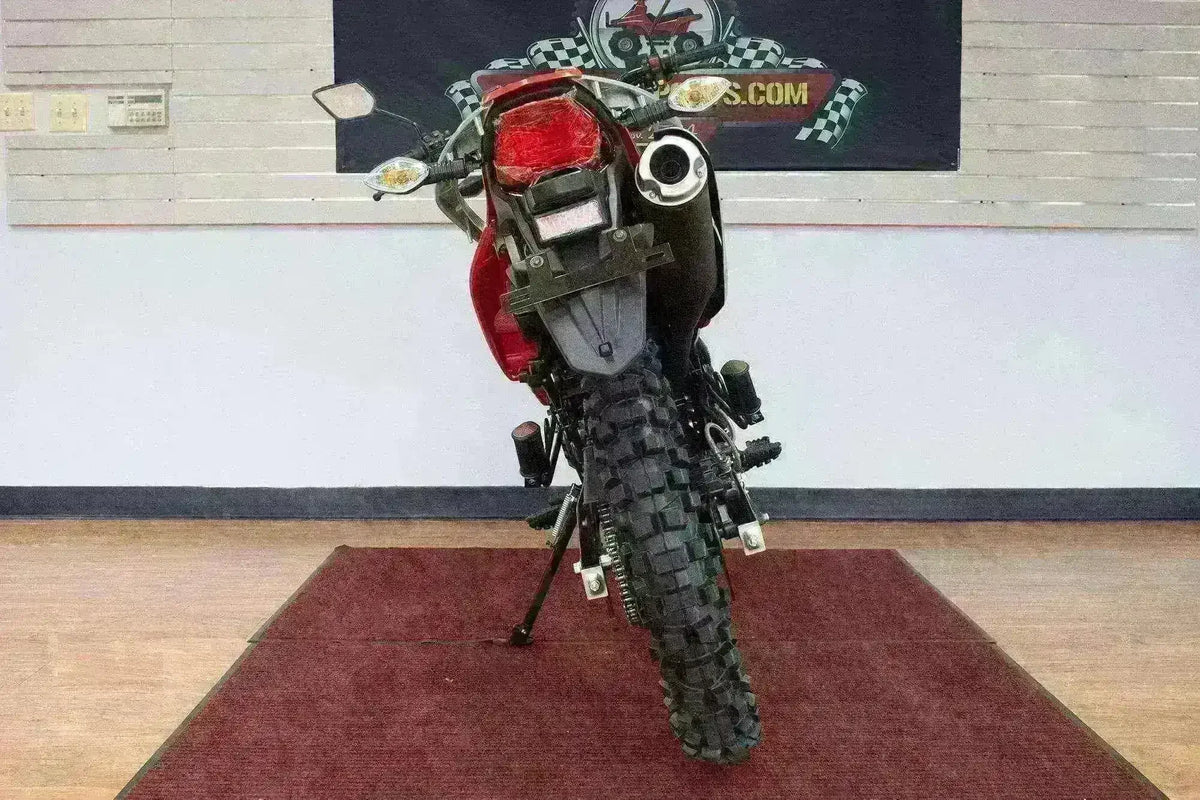 Rear view of a red 250cc enduro dirt bike with knobby tires and off-road exhaust