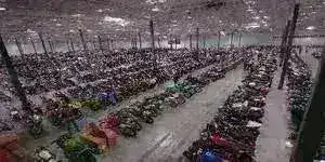 Large indoor warehouse filled with rows of scooters, ATVs, and motorcycles.