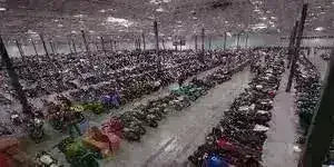 Large indoor warehouse filled with rows of scooters, ATVs, and motorcycles.
