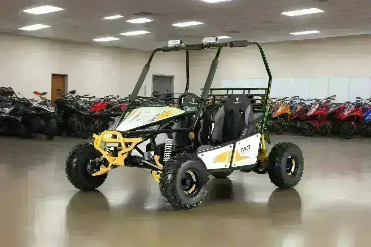 Yellow and white Triton two-seat go-kart with black frame and overhead lights, front three-quarter view in the showroom