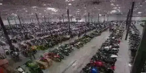 Large indoor warehouse with rows of ATVs, dirt bikes, go-karts, and scooters