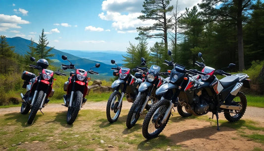 Group of dirt bikes parked on a scenic mountain trail surrounded by trees and blue sky