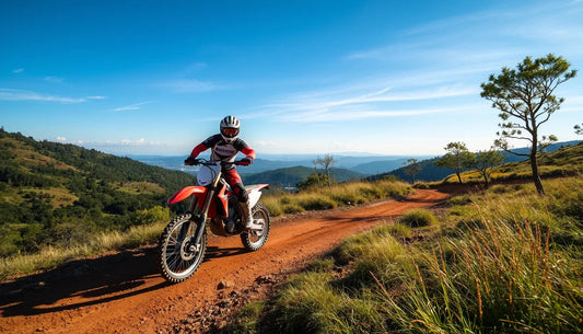 Rider on red dirt bike on scenic mountain trail under blue sky, off-road adventure.