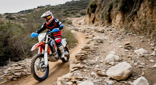 Rider in full gear on a dirt bike navigating a rocky off-road trail
