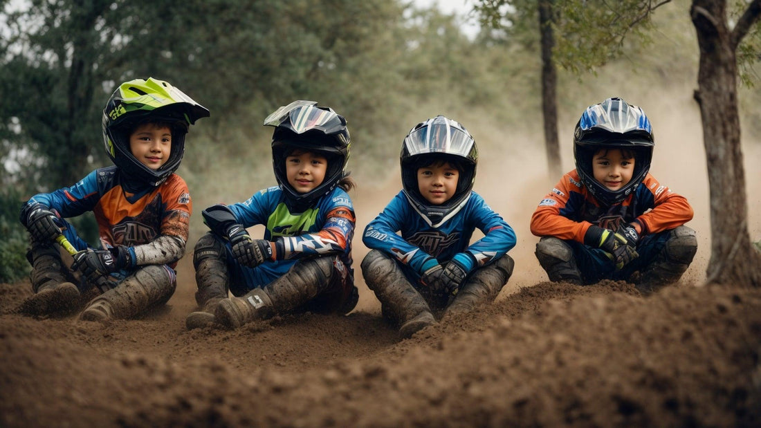 Four young children sitting on dirt motocross track wearing colorful youth motocross helmets and gear