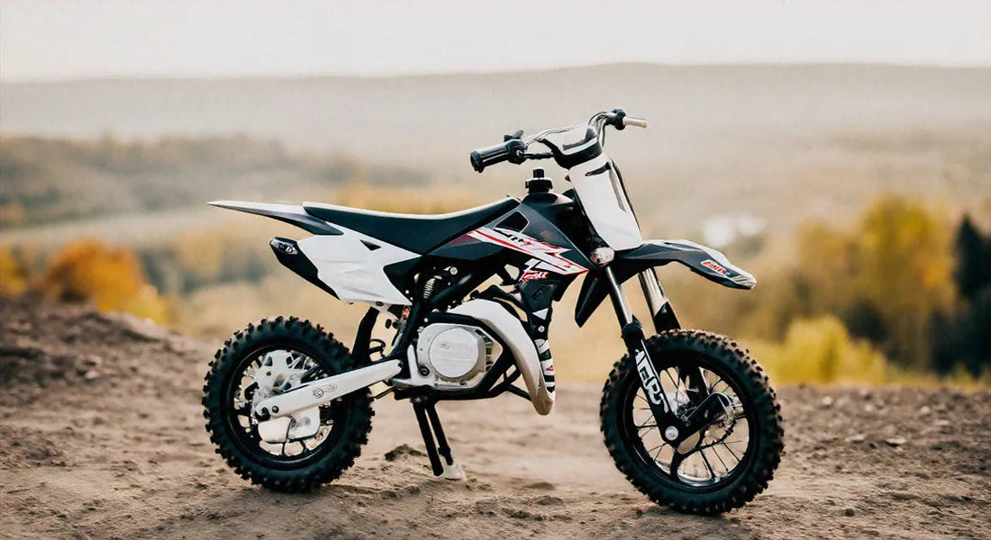 Black and white youth dirt bike with knobby tires on an outdoor dirt trail