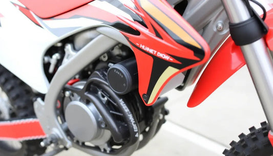 Close-up of red and black dirt bike engine, off-road tire, and front suspension