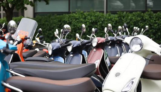 Row of colorful scooters parked outdoors, featuring various models and styles.