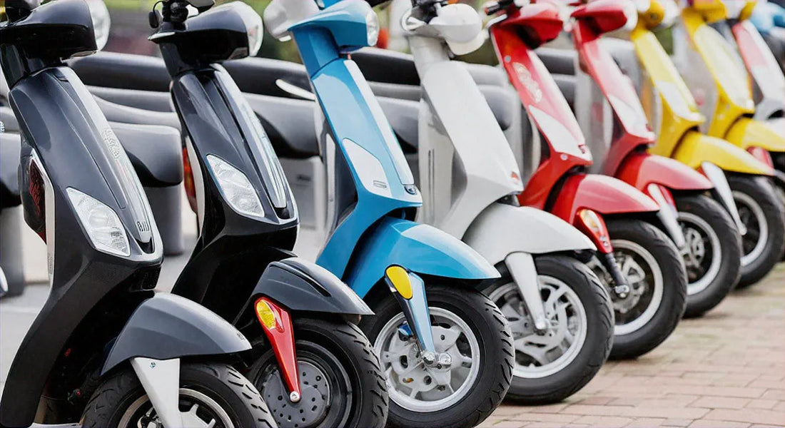 Row of colorful scooters parked outdoors, close-up on wheels and headlights