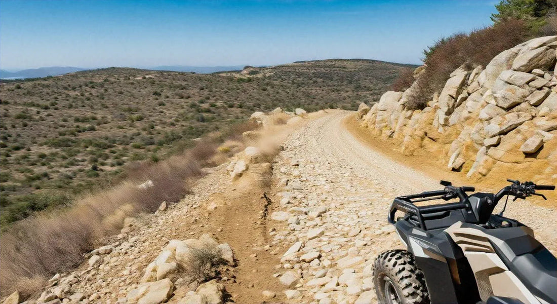 ATV on a rocky dirt trail in a rugged outdoor landscape with hills and boulders
