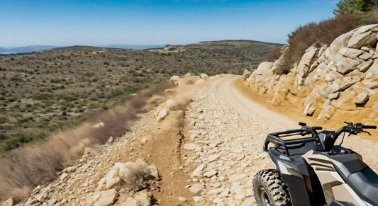 ATV on a rocky dirt trail in a rugged outdoor landscape with hills and boulders