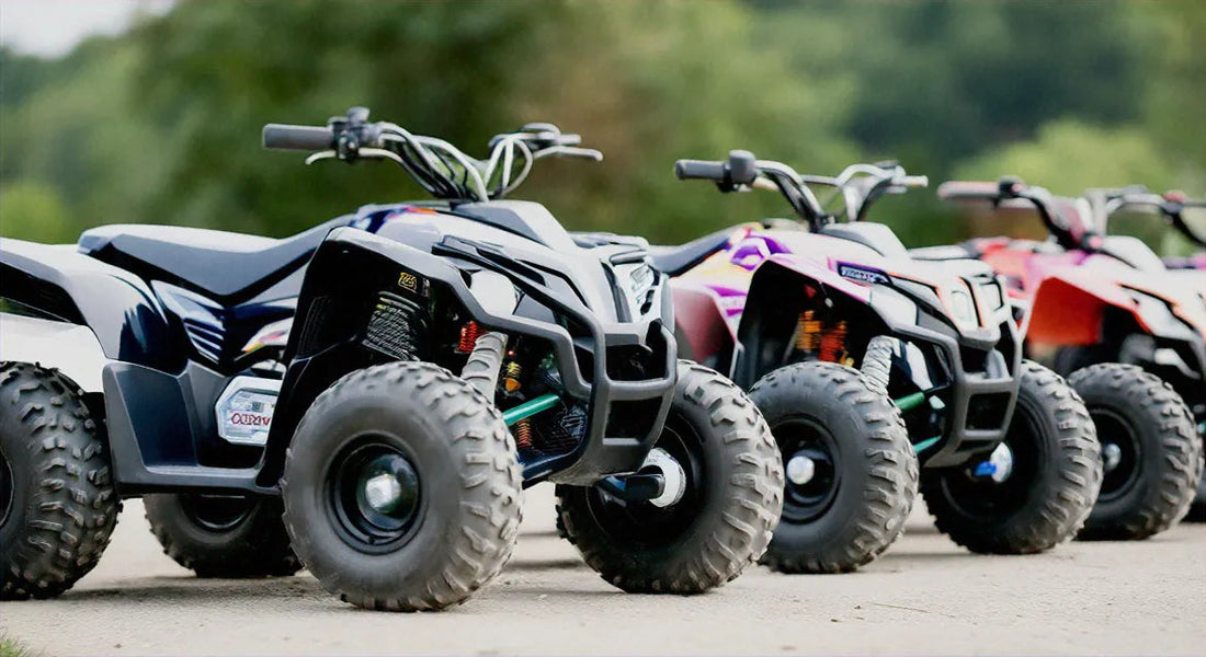 Three youth ATVs with rugged tires parked outdoors on a paved path