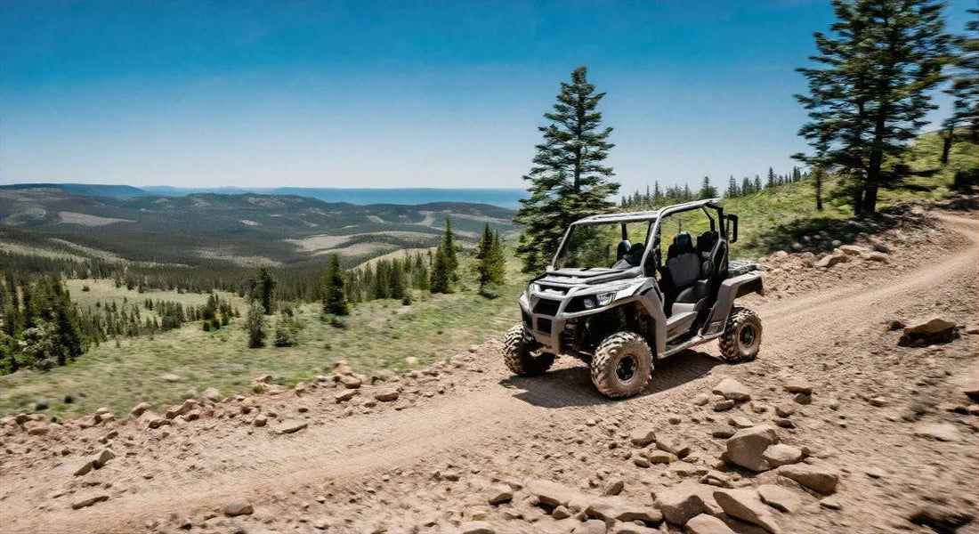 Side by side ATV driving on a rocky mountain dirt trail with scenic forest and valley view