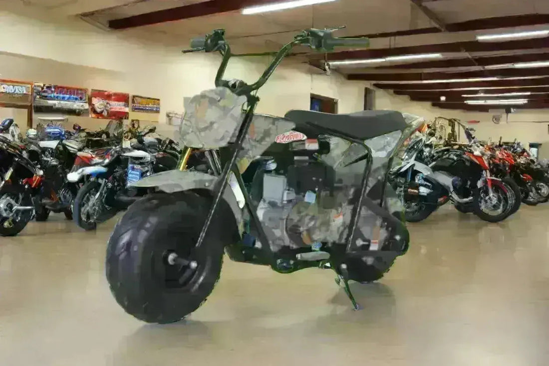 Camo mini bike with off-road tires displayed indoors among motorcycles and dirt bikes