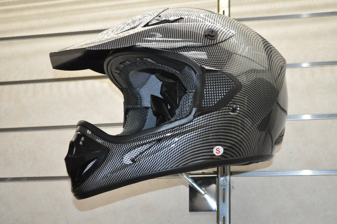 Carbon fiber motocross helmet with visor on display wall, off-road ATV safety gear