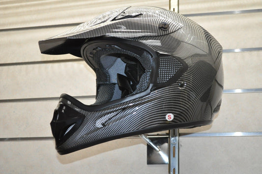 Carbon fiber motocross helmet with visor on display wall, off-road ATV safety gear