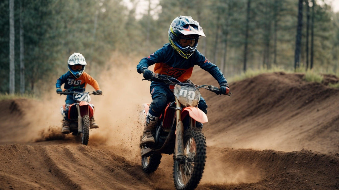 Two kids riding dirt bikes on a dusty off-road motocross track in a forested area