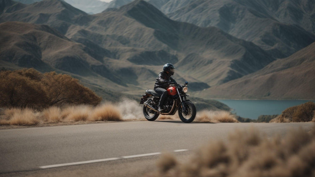 Rider on a red motorcycle cruising on a scenic road with mountains and lake in background