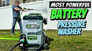 Man using EGO battery pressure washer outdoors on lawn near white fence