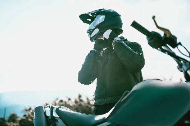 Rider in helmet and jacket preparing to ride a dirt bike outdoors