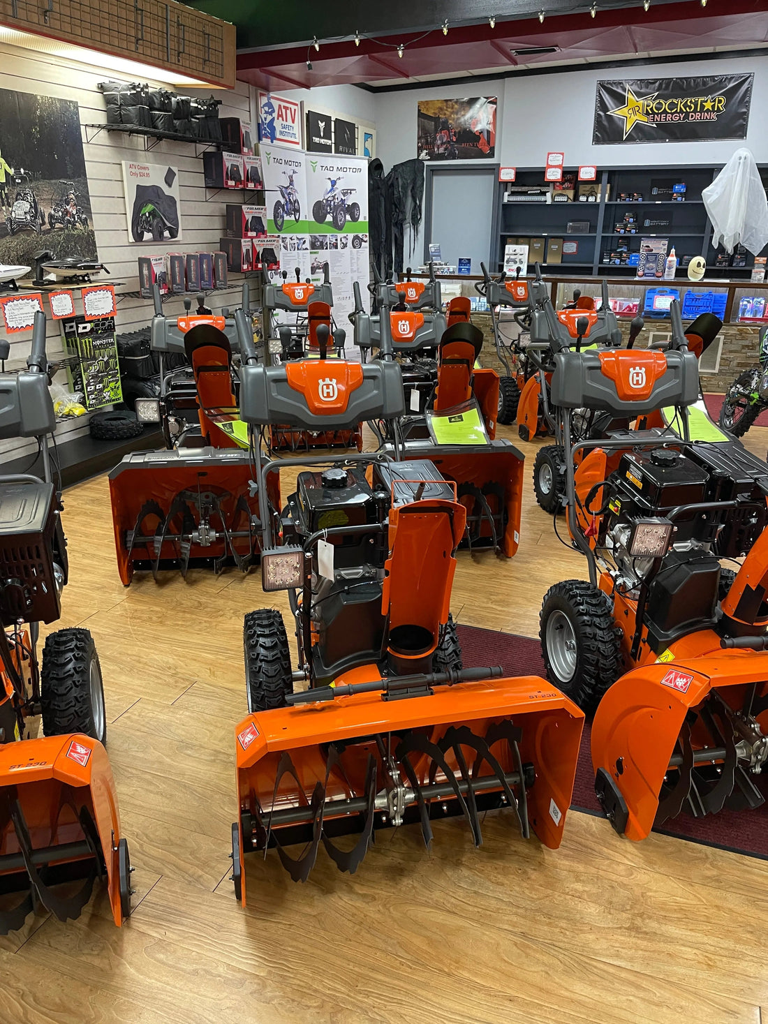 Multiple orange Husqvarna snow blowers displayed in a showroom with power sports equipment