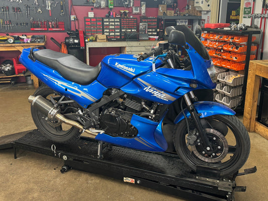 Blue Kawasaki Ninja sport motorcycle on maintenance lift in a garage workshop